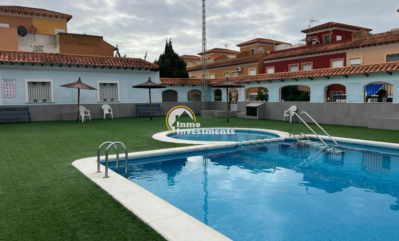 Gemeinschaftlicher Außenpool mit Leiter und Kunstrasen in einer Bungalowanlage in Torrevieja, Spanien