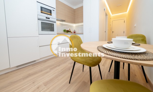 Open-plan kitchen-diner in Ciudad Quesada apartment with built-in oven, white cabinets, wood worktops and round dining table