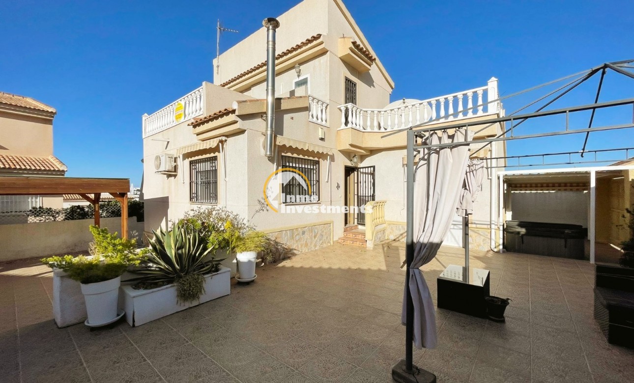 Außenansicht einer freistehenden Villa in Ciudad Quesada, Spanien, mit gefliester Terrasse, Topfpflanzen, oberem Balkon und eingezäuntem Eingang