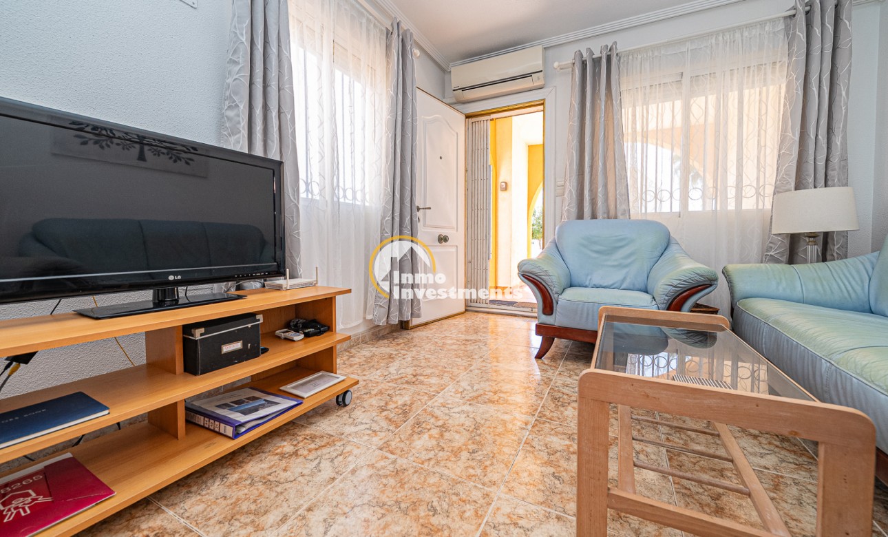 Living room in La Zenia apartment with TV unit, glass coffee table, leather sofas and patio doors to terrace