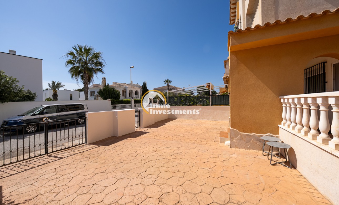 Paved front terrace and driveway at La Zenia apartment with gated entrance, palm tree and street parking