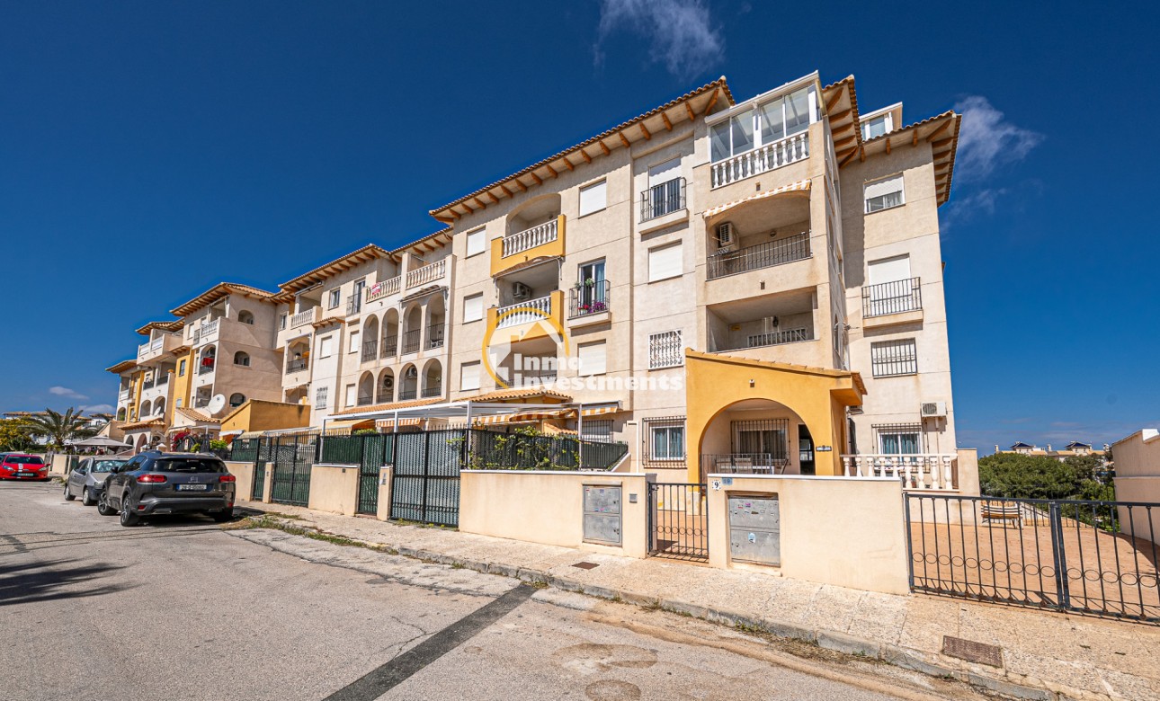 Apartment block exterior with balconies and gated frontage in La Zenia, Spain under clear blue sky