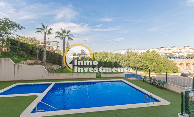 Communal outdoor swimming pool with sun terrace and palm trees for apartment in La Zenia, Spain