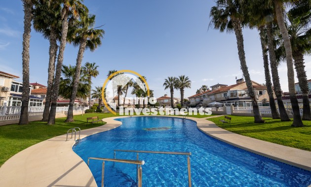 Curved outdoor pool with steps, sun loungers and palm trees at Playa Flamenca apartments, Spain
