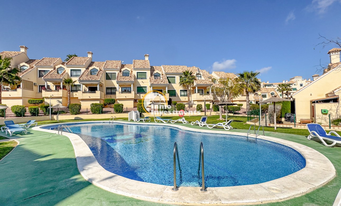 Gemensam pool med solstolar och anlagda trädgårdar i lägenhetskomplex i Orihuela Costa, Spanien