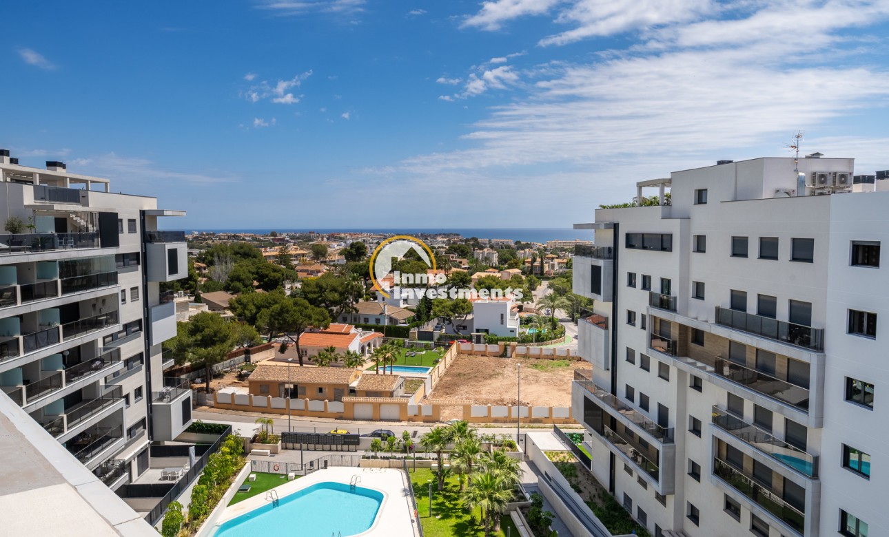 Campoamor penthouse outlook between contemporary apartments to communal pool, greenery and coastal skyline in Spain