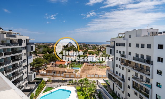 Campoamor penthouse outlook between contemporary apartments to communal pool, greenery and coastal skyline in Spain