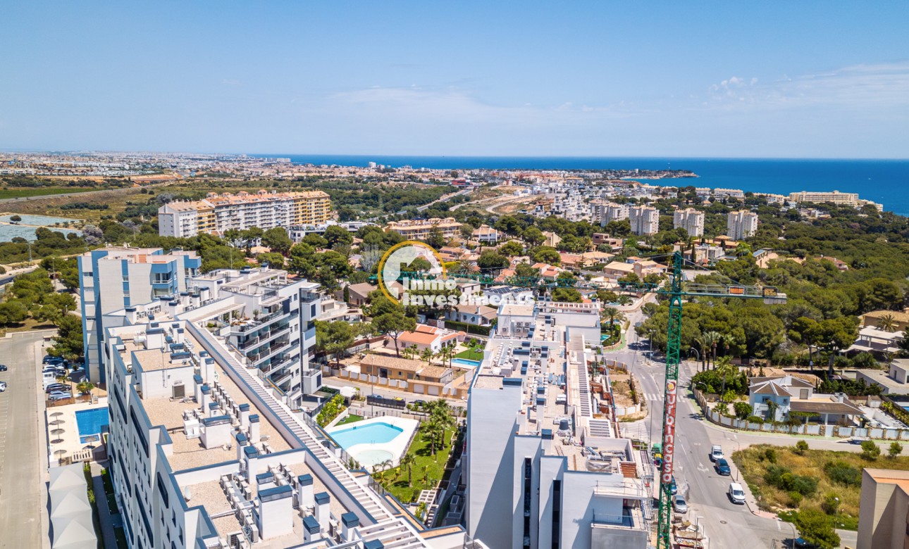 Drone shot of penthouse development in Campoamor, Spain, showing rooftop terraces, landscaped gardens and coastal sea views