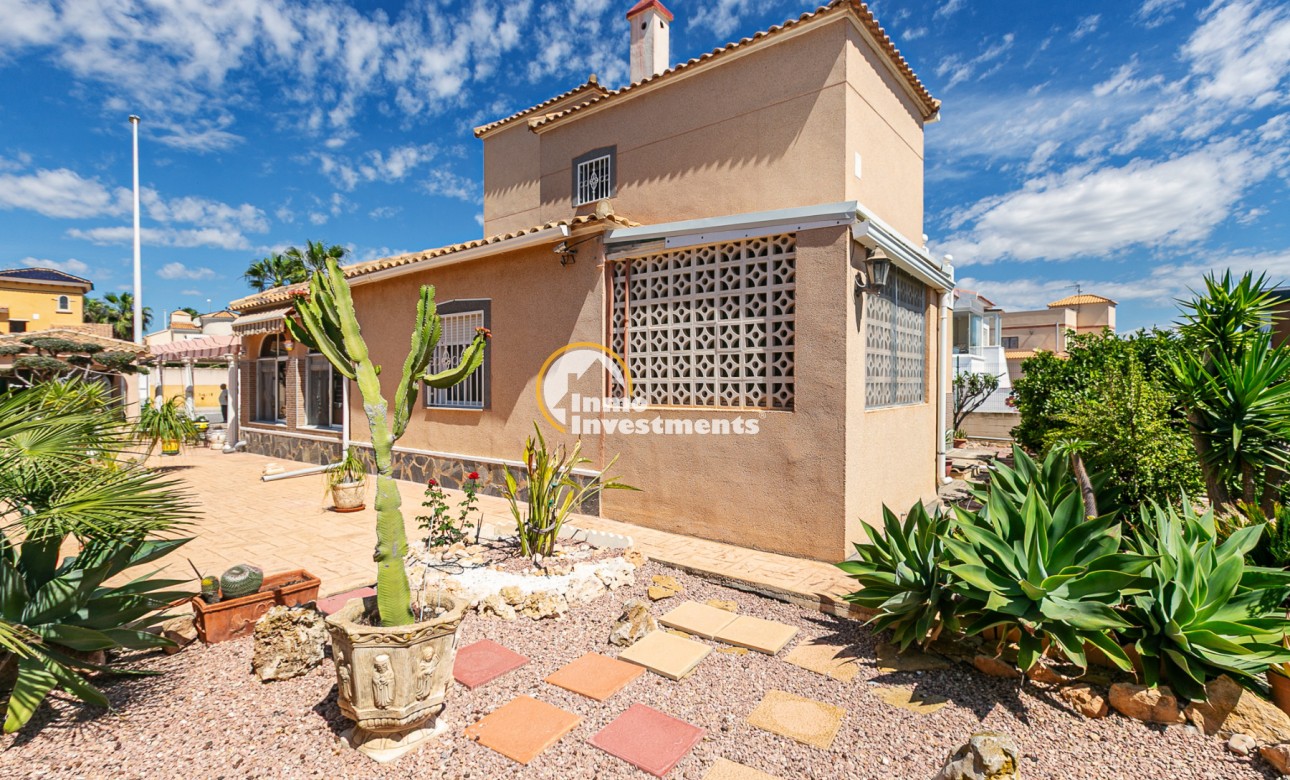 Außenansicht einer Immobilie an der Costa del Sol mit gefliester Terrasse, Kakteengarten und verglaster Veranda unter blauem Himmel