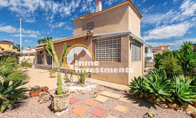 Außenansicht einer Immobilie an der Costa del Sol mit gefliester Terrasse, Kakteengarten und verglaster Veranda unter blauem Himmel