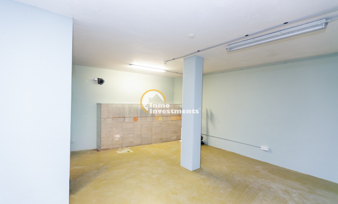Garage ou espace de stockage ouvert à Mil Palmeras, Espagne, maison quadruple avec murs clairs, éclairages au plafond et sol en béton