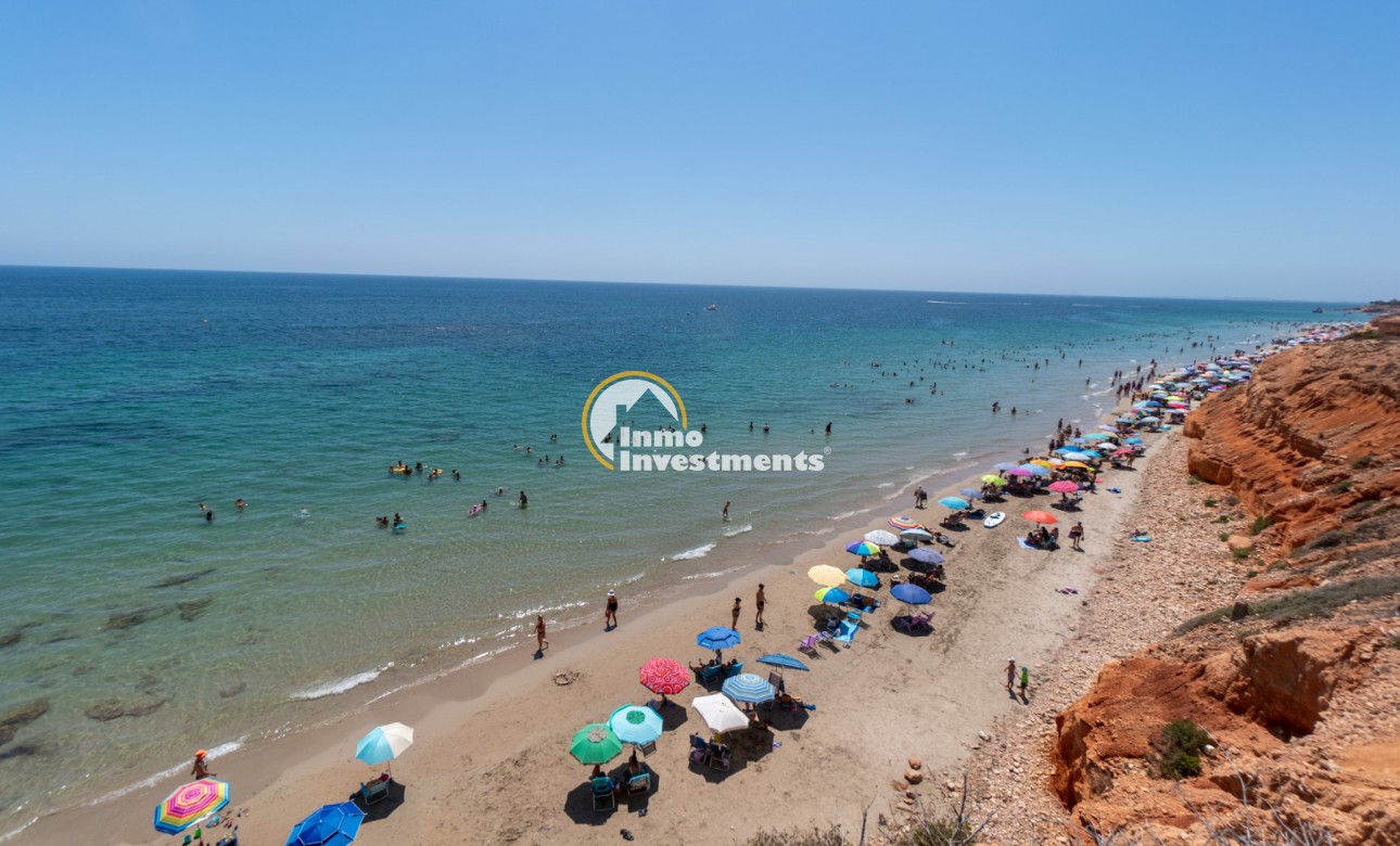 Beach and Mediterranean sea view near Mil Palmeras, Spain apartment, with parasols on sandy shore and rocky cliffs