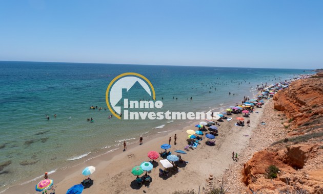 Beach and Mediterranean sea view near Mil Palmeras, Spain apartment, with parasols on sandy shore and rocky cliffs