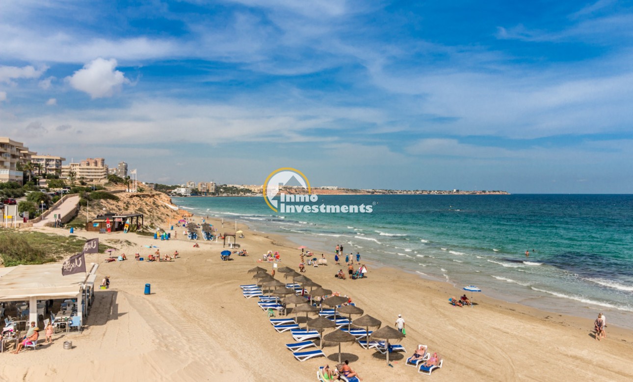 Beach and Mediterranean sea view near Mil Palmeras apartment, with sun loungers, parasols and sandy shoreline