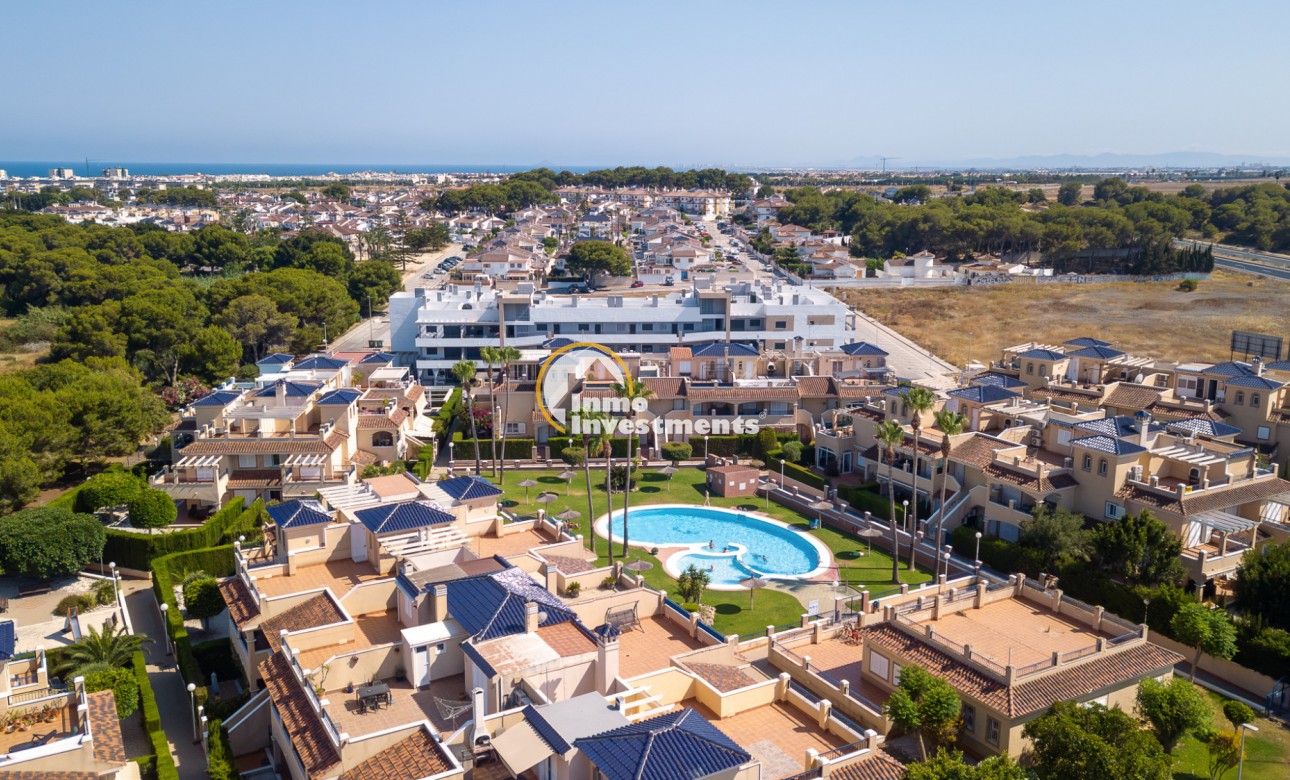 Drone shot of Mil Palmeras apartment development with landscaped gardens, pool and nearby woodland
