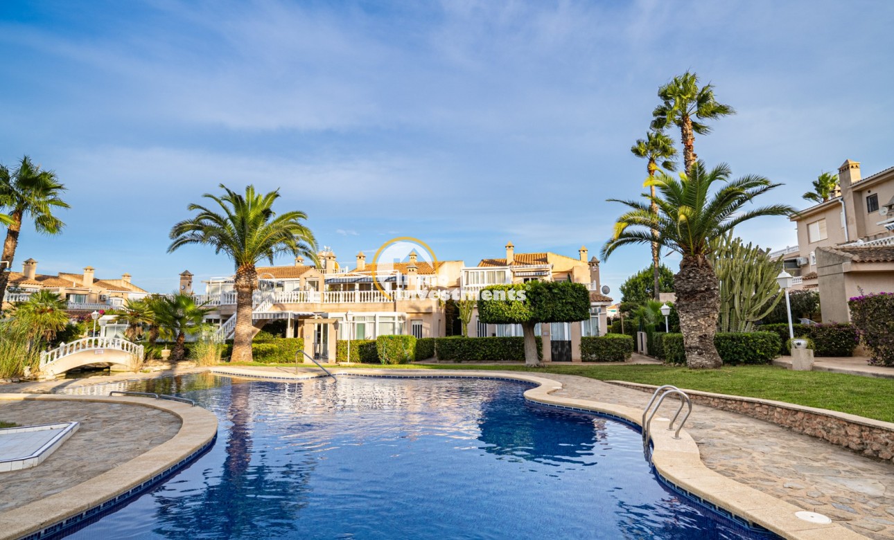 Piscina comunitaria con palmeras en el exterior de un dúplex en Playa Flamenca, España