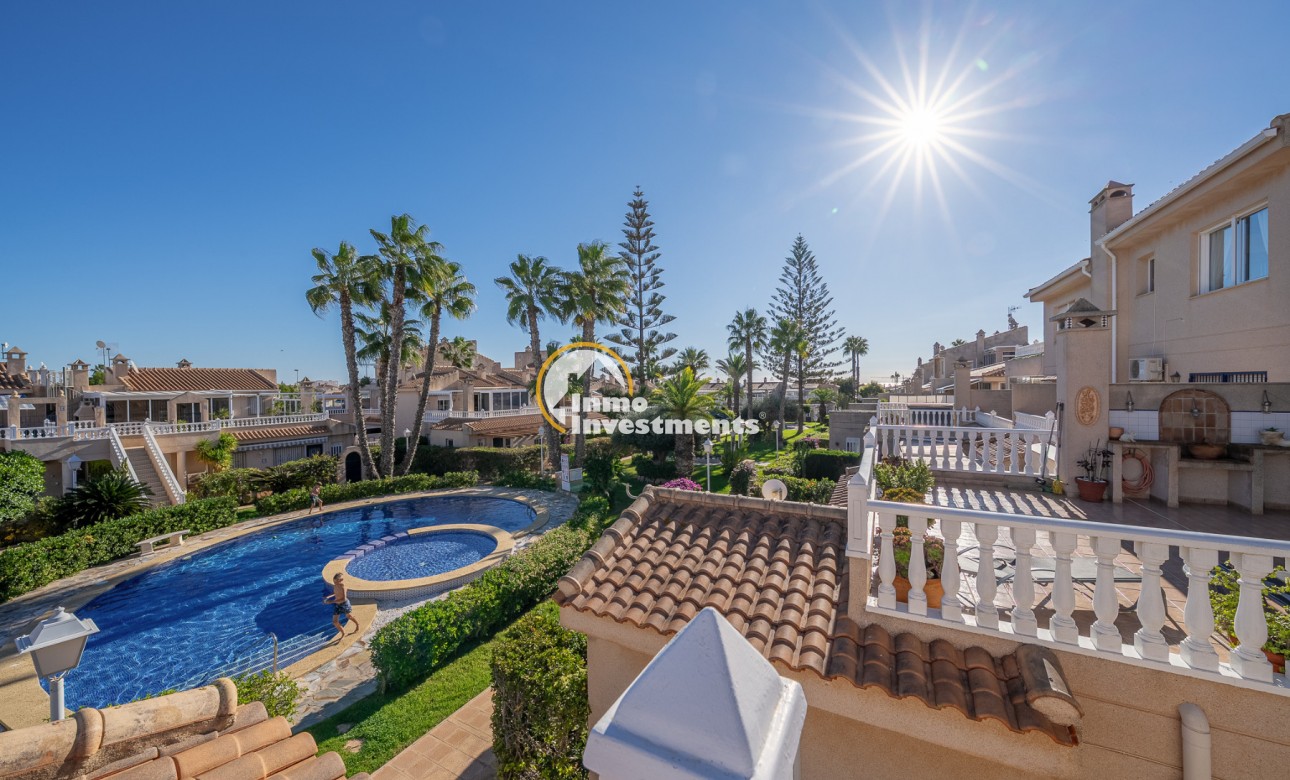 Sonnige Dachterrasse mit Balustrade mit Blick auf Pool, Palmen und benachbarte Häuser in einem Duplex-Apartment in Playa Flamenca