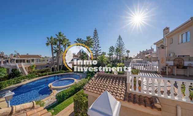 Sonnige Dachterrasse mit Balustrade mit Blick auf Pool, Palmen und benachbarte Häuser in einem Duplex-Apartment in Playa Flamenca